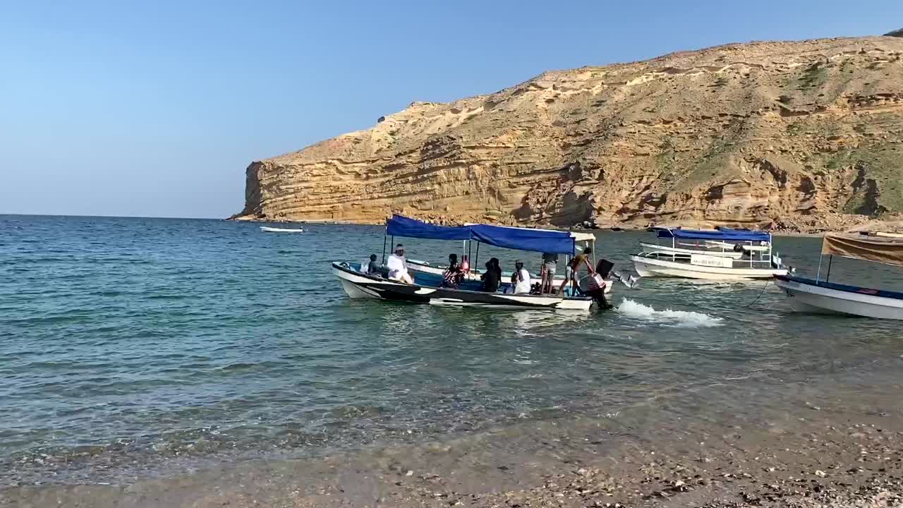 Güneşli bir günde genç bir kayıkçı, turistleri Qantab plajından taşımak için servis teknesini kullandı.
