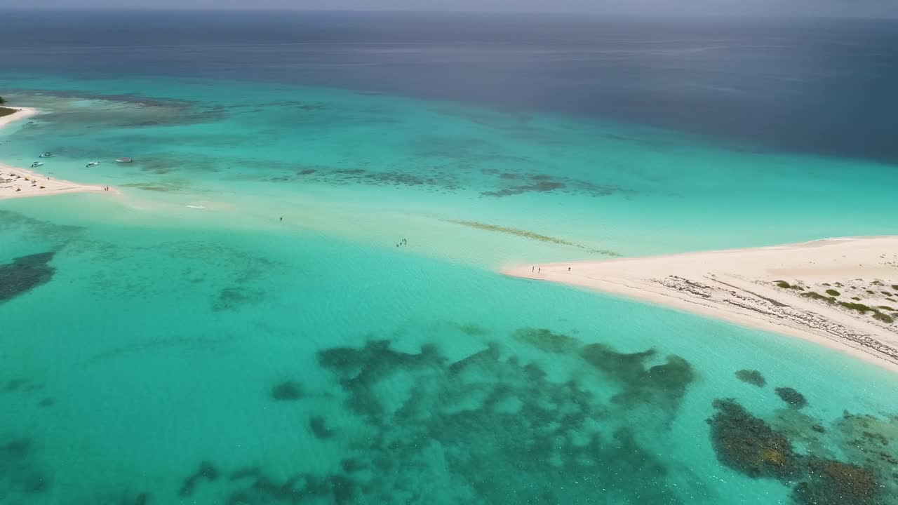 la gente camina inundado banco de arena cayo de agua isla en aguas poco profundas, vista aérea textura de agua turquesa y arrecife de coral