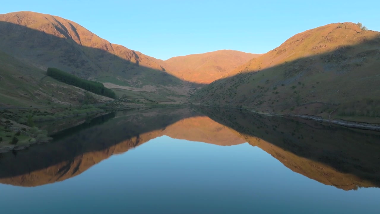 Haweswater Rezervuarı, İngiliz Göller Bölgesi, Cumbria, Birleşik Krallık. HarterFell, High Street ve Kidsty Pike, gün doğumu ışıklarıyla yıkanmış ve ayna gibi sakin göle yansımış.