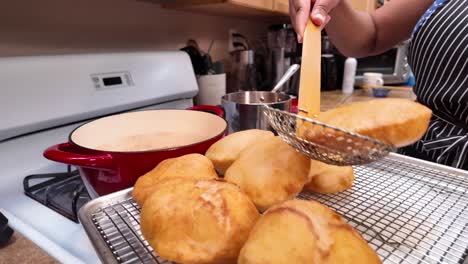 scooping indian bhatura frybread puffs out of the hot oil - chana masala series