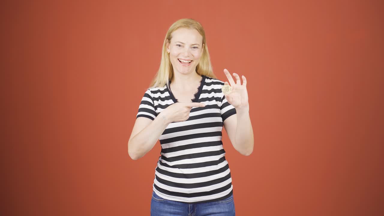 mujer sosteniendo bitcoin y mostrándolo.