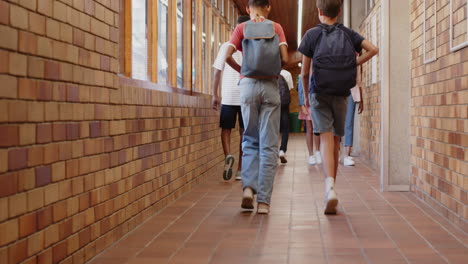 walking in school hallway, students talking and carrying backpacks with teacher