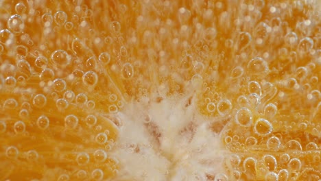 a piece of a juicy orange under the water with air bubbles.