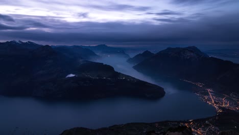 Day-to-night-time-lapse-of-Lake-Lucerne-as-seen-from-Fronalpstock,-Switzerland-with-a-panoramic-view-of-the-fjords-and-mountain-peaks