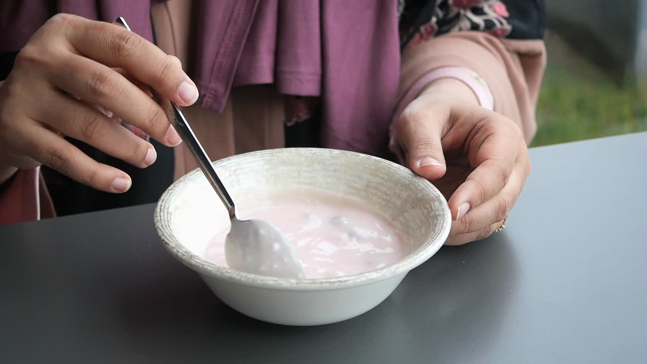 mujer comiendo yogur rosa en un tazón