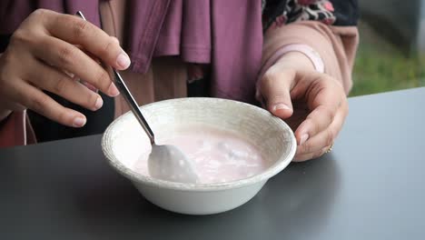 woman eating pink yogurt in a bowl