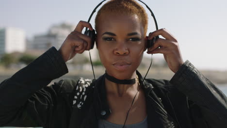 portait of young african american woman on sunny beachfront puts on headphones listening to music