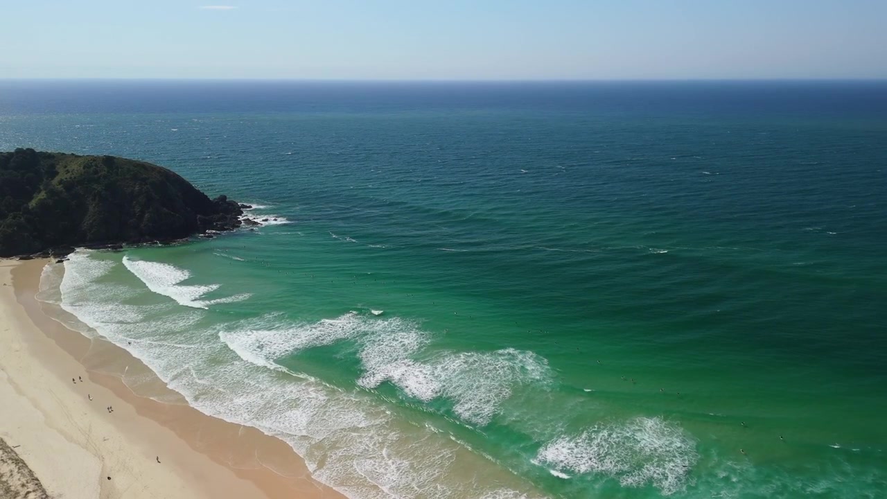 Veduta aerea con drone di persone che fanno surf sulla spiaggia posteriore di Byron Bay