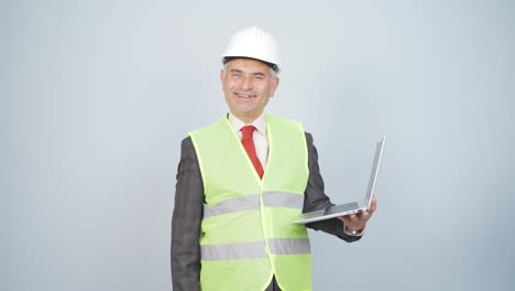 engineer holding laptop laughing at camera.