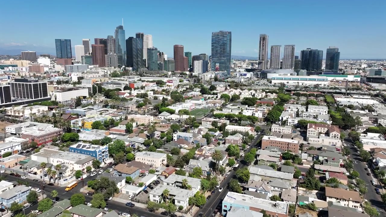 Los Angeles, California, USA: Riprese con drone a bassa quota che catturano lo skyline del centro di Los Angeles con grandi grattacieli che si ergono sopra un consolidato quartiere urbano messicano