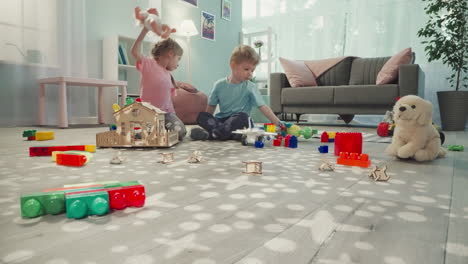 siblings play with baby doll and robot dinosaur in nursery