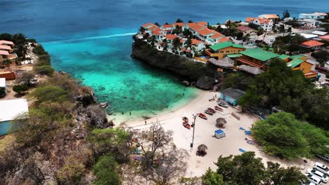 Die-Drohne-Fliegt-über-Einem-Kleinen-Strand-Zwischen-Einem-Dorf-In-Curaçao,-Luftaufnahmen-4K