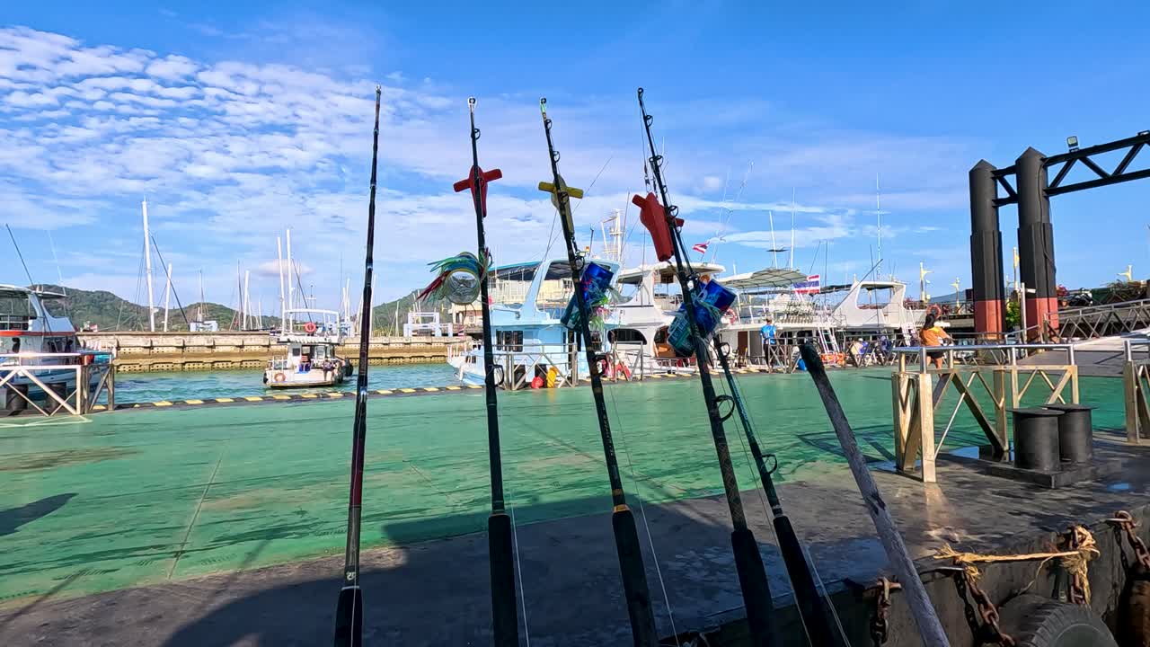 Fishing boats docked at Rawai Beach, Phuket, under clear blue skies. Calm waters and vibrant colors create a serene atmosphere