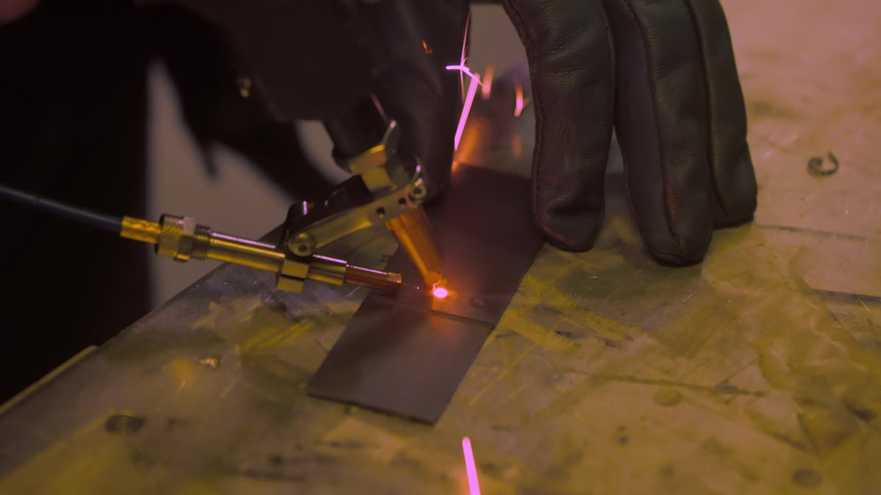 Laser welding machine with hand hold gun. Laser welding is shown in close-up.