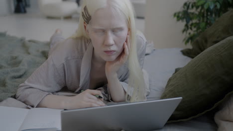 young woman studying on a laptop in bed