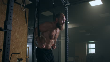 fitness-bodybuilding-and-people-concept-young-man-doing-push-ups-on-gymnastic-rings-in-gym.-Handsome-young-sportsman-with-artificial-leg-doing-push-ups-with-hanging-rings-of-gymnastics-ladder-at-gym