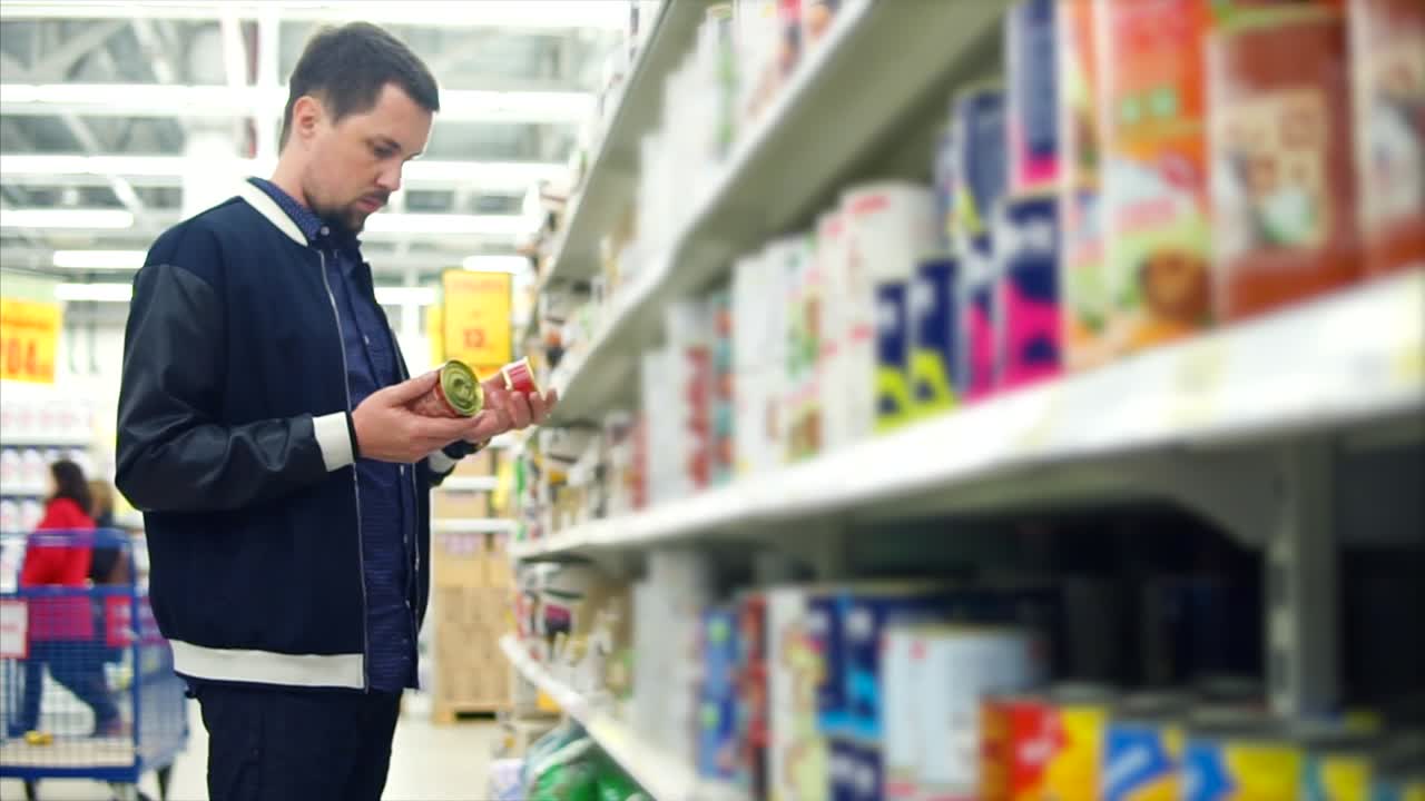 hombre comprando productos enlatados en una tienda de comestibles