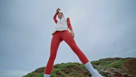 sporty girl posing landscape bottom view. slim strong woman standing gray sky