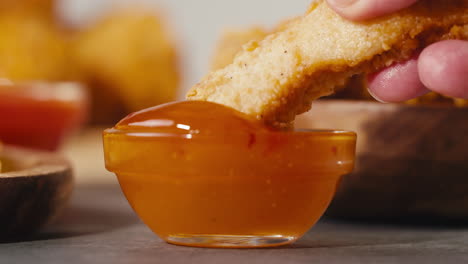 dipping crispy fried chicken in orange sauce