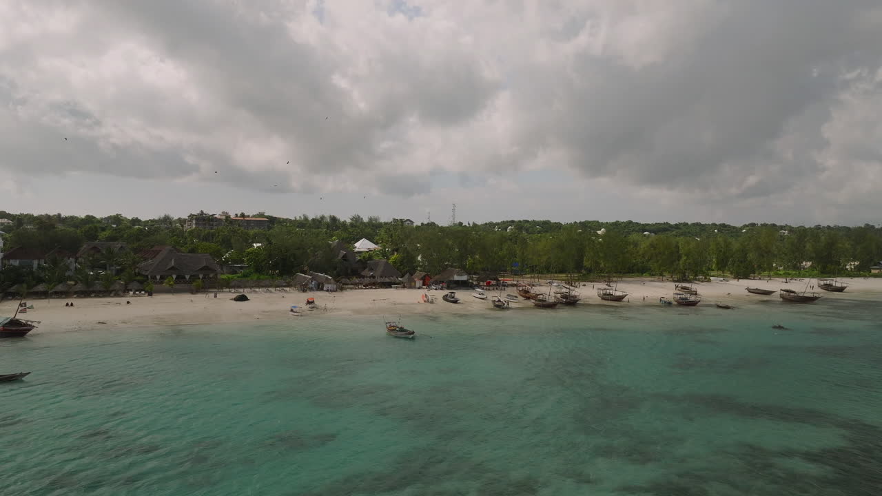 Tekneler, insanlar ve bulutlu gökyüzü ile güzel kumlu plajın ve turkuaz okyanusun drone görüntüsü, Zanzibar, Kendwa, Afrika, 30 fps hızında çekildi.