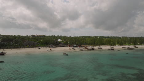 Drone-view-of-beautiful-sandy-beach-and-turquoise-ocean-with-boats,people-and-clouds-sky,-Zanzibar,-Kendwa,-Africa,-shot-at-30-fps