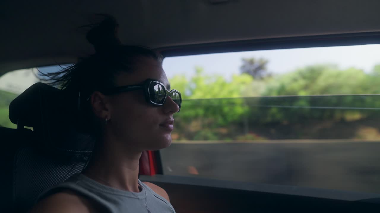 Woman in sunglasses looking out car window during a journey