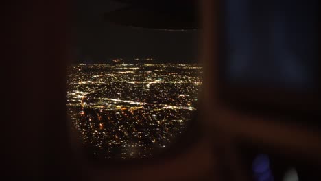 Vista-Del-Paisaje-Urbano-Moderno-Iluminado-Por-La-Noche-Desde-La-Ventana-Del-Avión