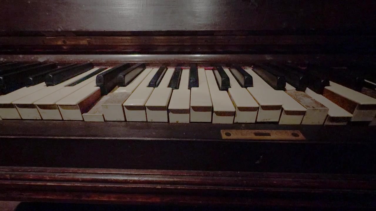 Vintage piano with moving ivory keys in a haunted mansion room. This mechanical instrument creates a spooky supernatural vibe for horror, mystery, or period-piece films, close-up