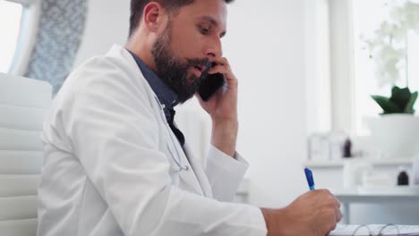 vista portátil del médico hablando por teléfono móvil en el consultorio del médico