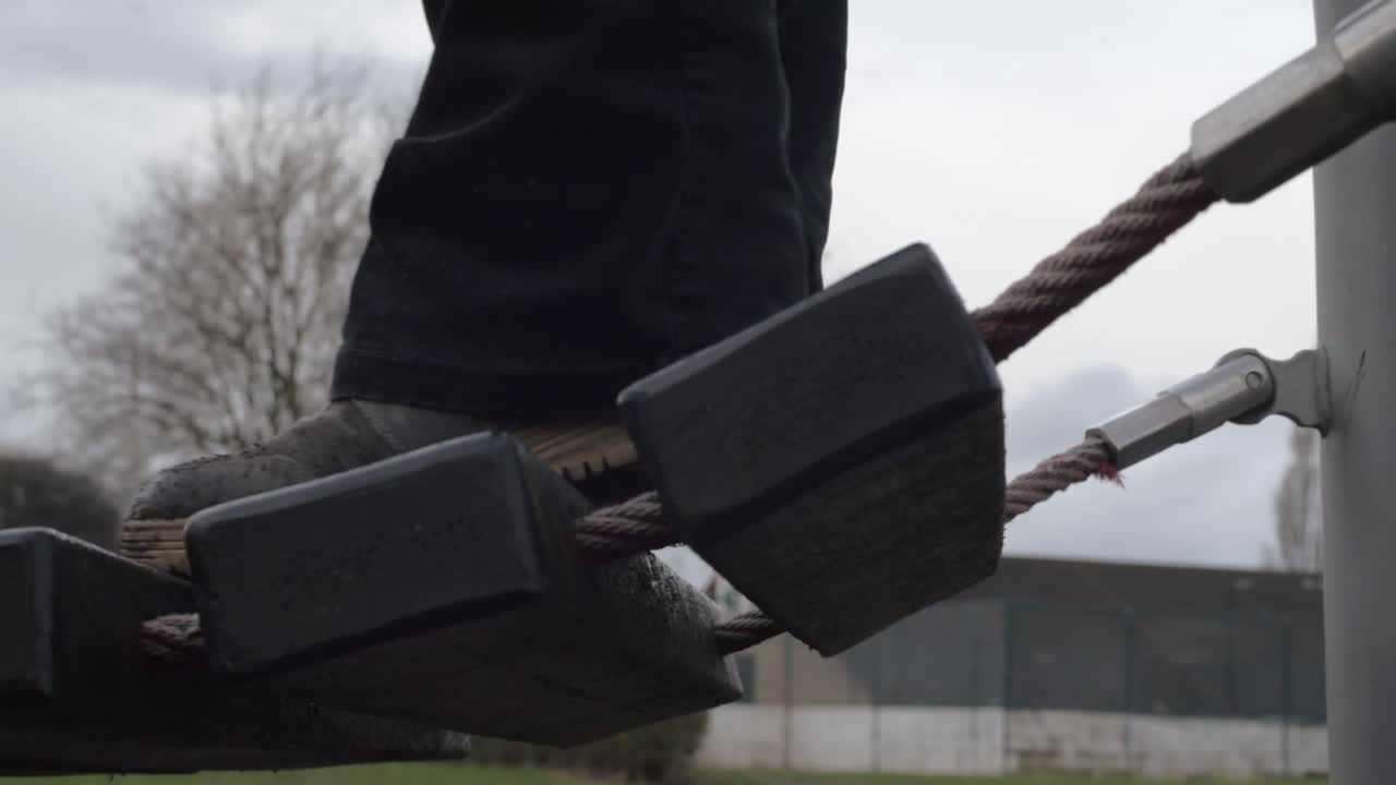 Feet waiting to cross rope bridge in park