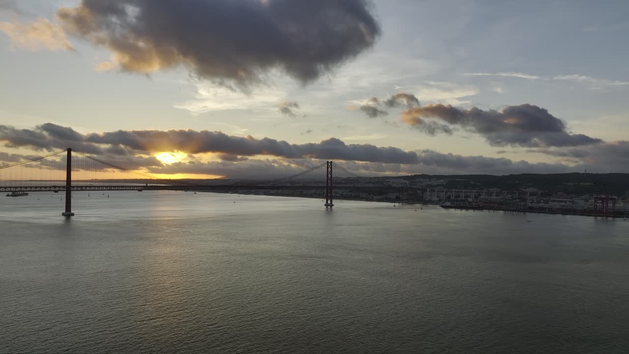 Drone shot rising from Almada, Tangus river, with view over the bridge &amp;quot;Ponte 25 Abril&amp;quot;, at sunset