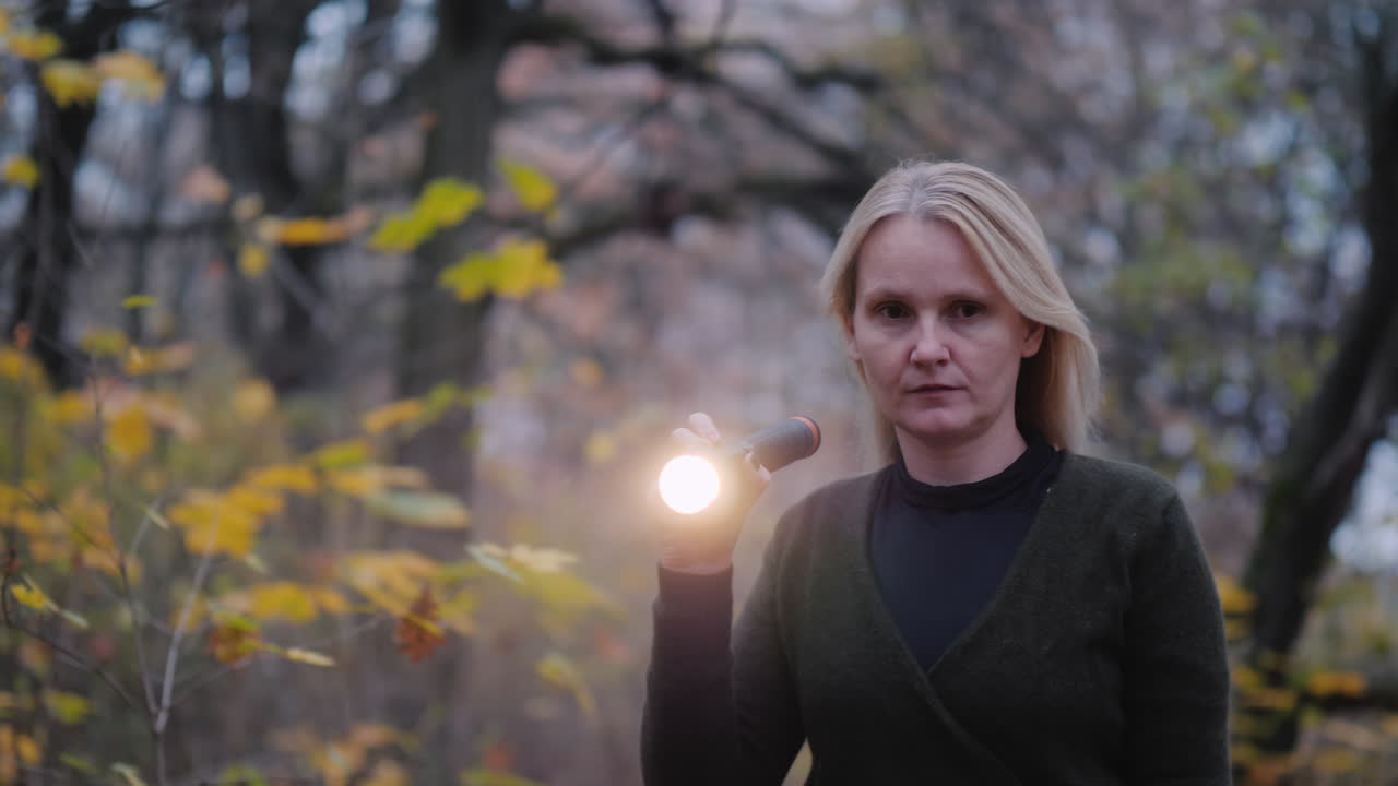 поиски в лесу - женщина с фонариком идет по темному лесу