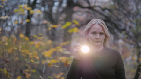 searches in the forest - a woman with a flashlight walks through a dark forest