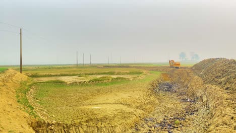 Trench-dug-by-excavator-in-a-rural-landscape,-Bangladesh,-panning