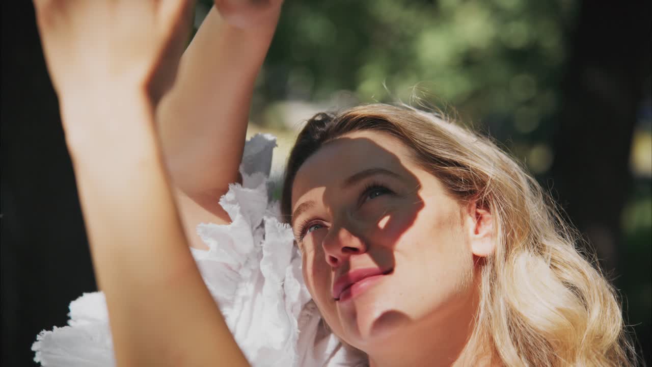 Blije jonge vrouw schermt gezicht af van de zon in het park