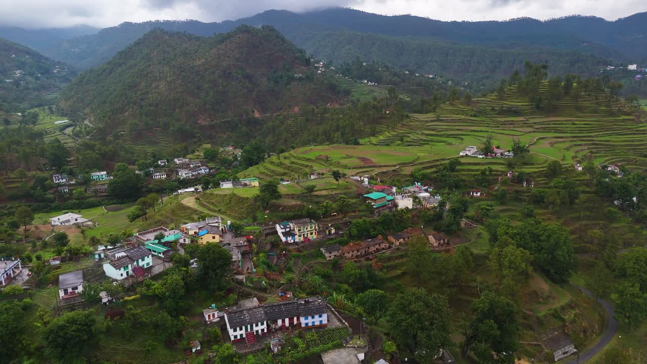 Aerial drone shot offering a top-down view of a small village blending into the mountainous landscape.