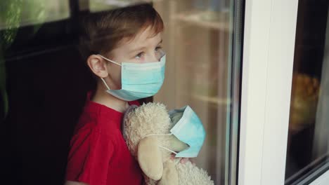 a boy with a toy in a mask looks out the window