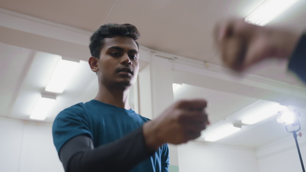 Brother in blue shirt playing hand trick indoors while other player misses move, showing focus, challenge, and playful competition during interactive moment