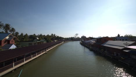 calm river gently flowing through a village in thailand on a bright sunny day