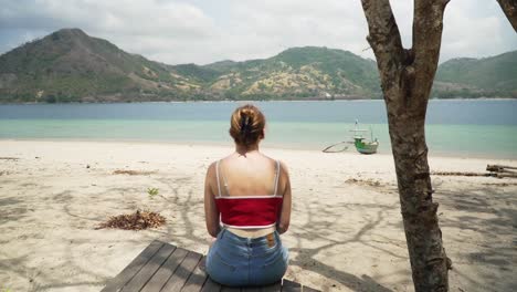 Young-Attractive-Woman-Sitting-on-Wooden-Dock-on-Tropical-Beach-in-Indonesia