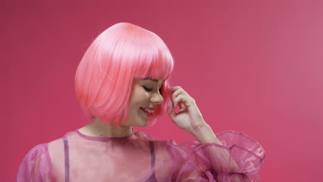 portrait of a beautiful woman wearing a pink wig dancing and laughing