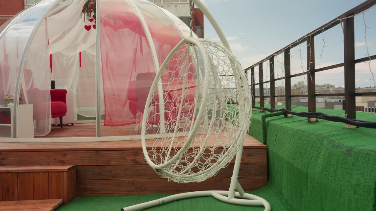 terrazza panoramica con sedia sospesa, cupola di vetro con interni rosa, ponte in legno, manto erboso verde, ringhiera in metallo e vista sullo skyline urbano, intimo salotto moderno ideale per una vacanza romantica o un rifugio tranquillo