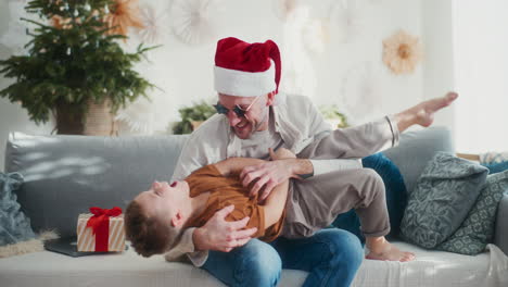 dad and son playing on couch during christmas