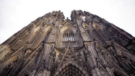 a breathtaking upward view of the intricate gothic facade of cologne cathedral, showcasing its detailed architecture and grandiose design under a cloudy sky.