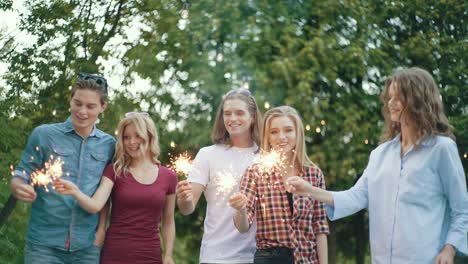 happy friends with sparklers having fun outdoors