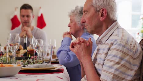 Familia-Caucásica-Sentada-En-La-Mesa-Del-Comedor-Rezando-Juntos-Antes-Del-Almuerzo