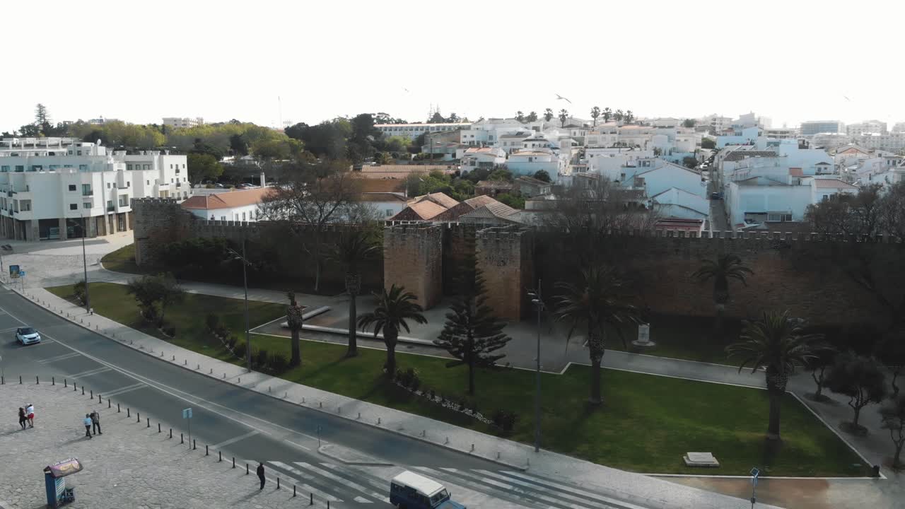Middelaldermurer ved Lagos slott omgitt av moderne bybilde i Algarve, Portugal – Lavvinklet luftfoto med sirkulær bevegelse.