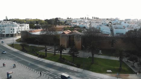medieval walls of castle of lagos surrounded by modern cityscape in algarve, portugal - aerial orbit low angle shot