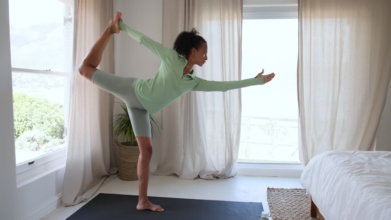 Woman practicing yoga on mat at home, focusing on balance and posture
