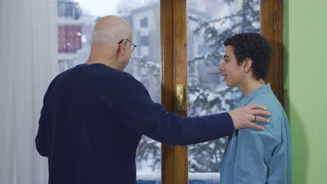 el abuelo y el nieto charlan felizmente frente a la ventana.